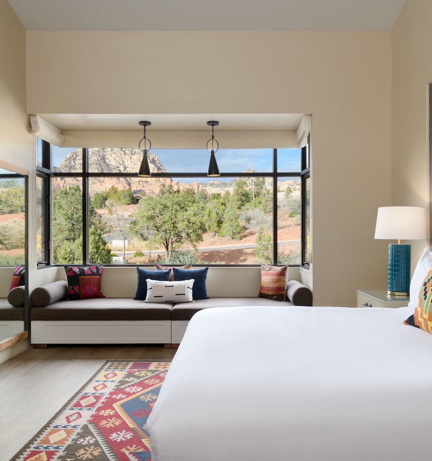 Modern bedroom with large bed, colorful rug, and a scenic window view.