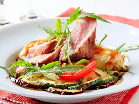 The image features a plated dish with seared tuna, grilled vegetables, and arugula, drizzled with balsamic reduction, served on a white plate.