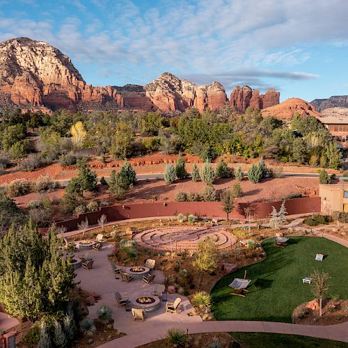 The image shows a picturesque landscape with red rock formations, a green garden area, and buildings, likely a resort, nestled in a desert environment.