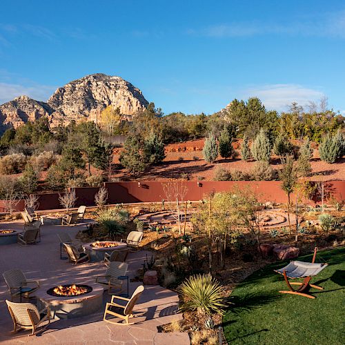 An outdoor seating area with fire pits, tables, chairs, and hammocks is set against a red rock desert landscape with a mountainous backdrop ending the sentence.