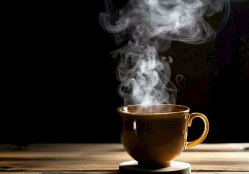 A steaming cup of coffee sits on a wooden table, with steam rising elegantly against a dark background.