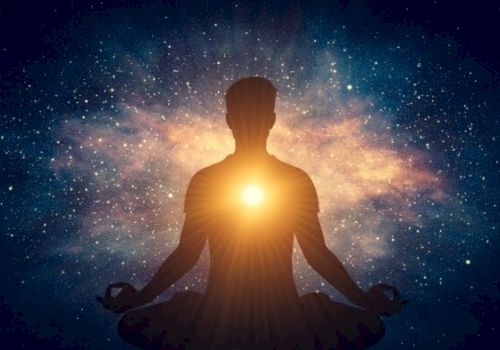 A silhouette of a person meditating with a glowing light at the heart, surrounded by a cosmic, starry background.