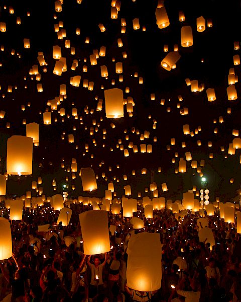 A crowd releases glowing lanterns into the night sky, creating a magical and illuminated scene during a lantern festival.