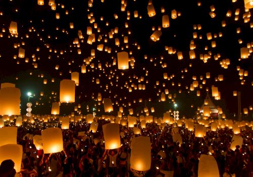 A crowd releases glowing lanterns into the night sky, creating a magical and illuminated scene during a lantern festival.