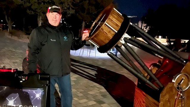 A person stands outside at night beside a large telescope, with a sign that reads "RED ROCK STARGAZING." Trees and a dark sky are in the background.